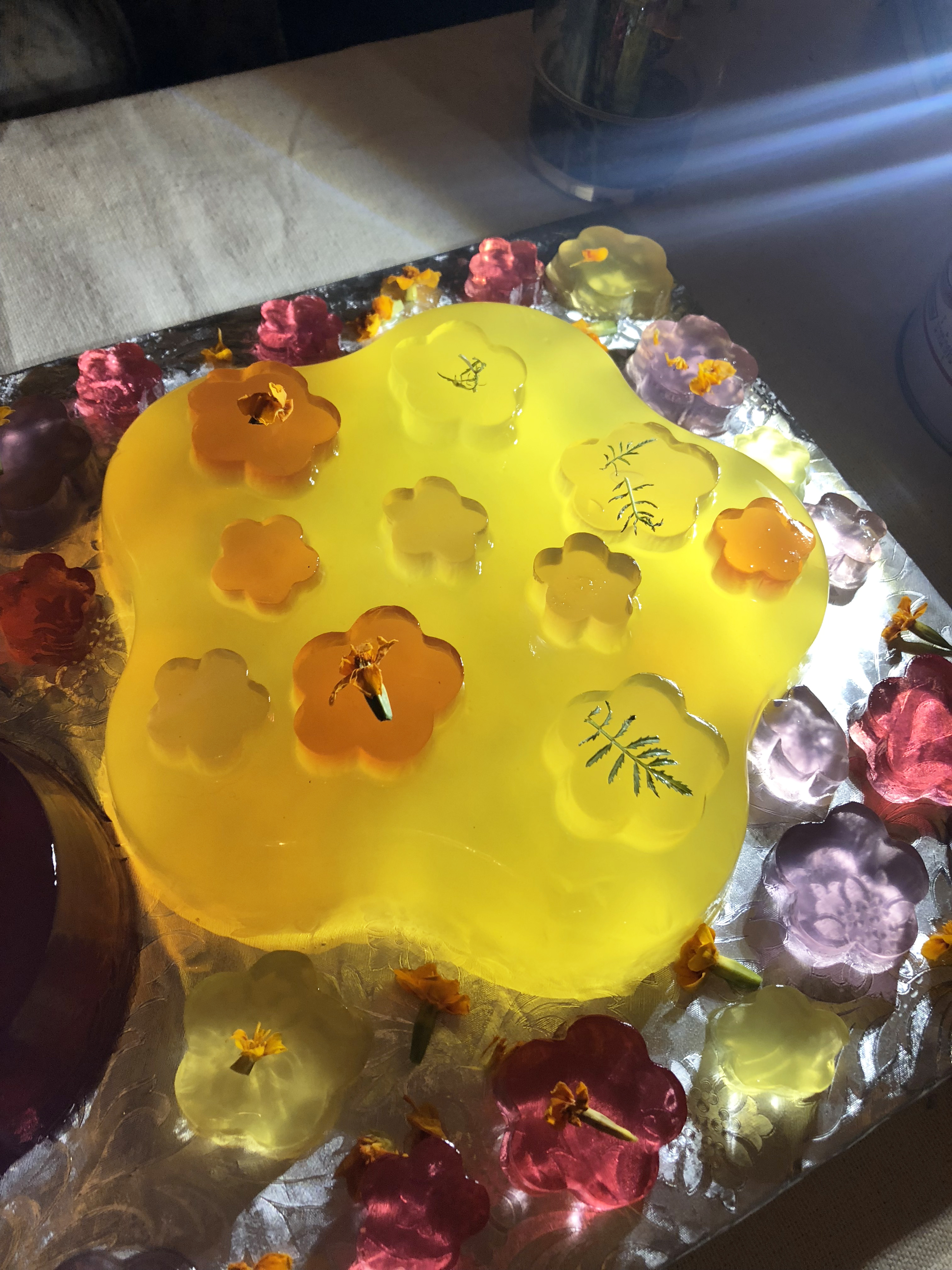 Detail of a brightly colored yellow jello cake in the shape of a flower on an alliuminium tray
